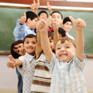 Kinder im Klassenraum nit Daumen hoch
